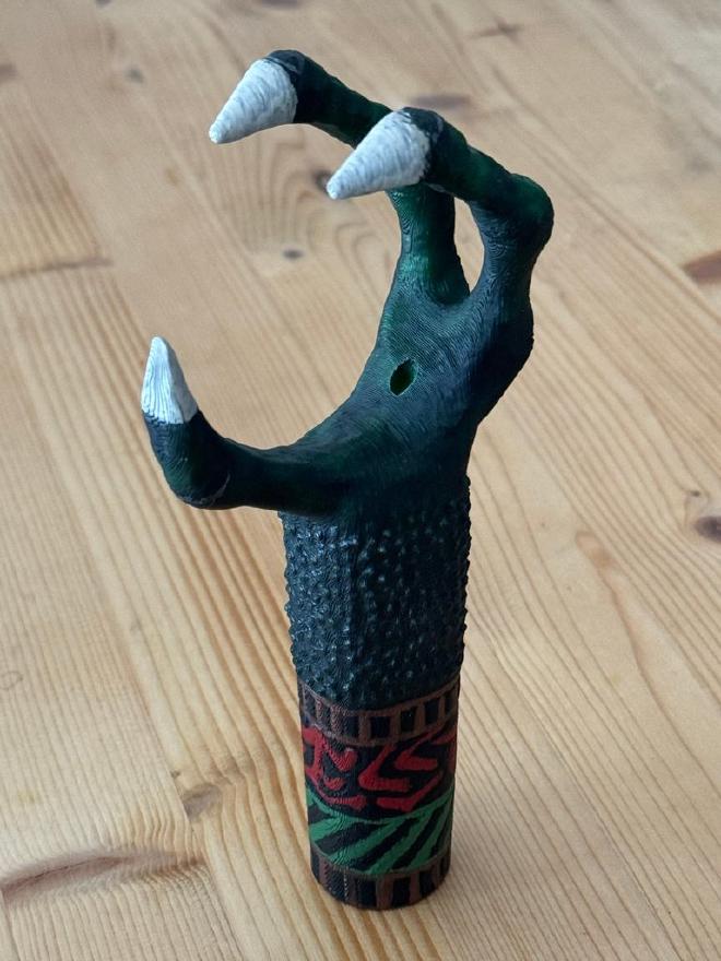 Claw painted in black, with details in red and green. Fingertips are white